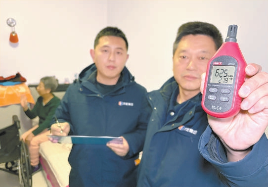 供热管家段勇（右一）和同事入户测量，居民家室温21.9℃达标。