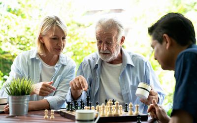 Woman and man playing chess with an older man