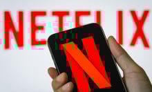 a person holds a smartphone in vertical orientation displaying the red N logo of Netflix